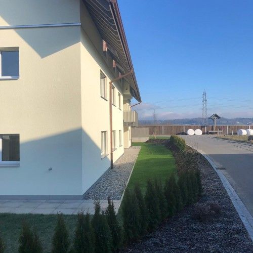 Gebäude mit gepflegtem Rasen und Heckenbepflanzung