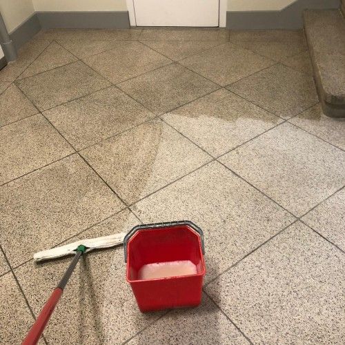 Treppenhausreinigung mit Mopp und Eimer auf Granitplatten